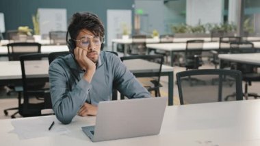 Sıkılmış Arap adam, kulaklıklı Hintli servis müdürü, video konferansında Webinar 'a bak, dili öğren zor iş sıkıntısı ile çalışarak kişisel eğitim mesleki becerilerini geliştir.