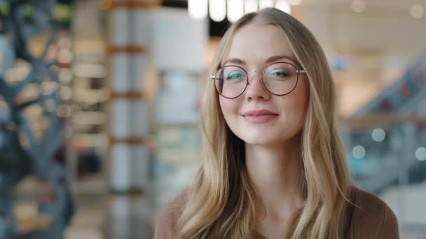 Kepala ditembak bahagia potret gadis Kaukasia berkacamata wanita muda puas dengan layanan oftalmologi Millennial pirang dengan senyum sehat putih melihat kamera percaya diri model berpose di dalam ruangan — Stok Video