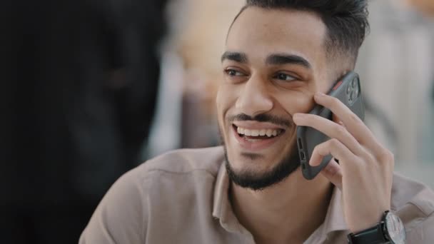 Cep telefonuyla konuşan mutlu, güler yüzlü, genç bir Arap 'ın portresi. Dost canlısı, tasasız adam, uzaktan iletişim için modern bir cihaz kullanarak telefona cevap veriyor. Keyifli sohbetler paylaşıyor. — Stok video
