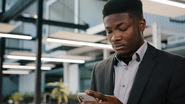 Homme africain réfléchi courtier professionnel utilisant des applications mobiles pour les ventes en ligne bavarder avec un ami rendant l'ordre surfer sur Internet analyste concentré lecture d'informations dactylographier message dans le réseau social — Photo