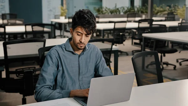 Joven escritor empleado árabe meticulosamente escribir teclado portátil copiar texto en forma electrónica centrado hombre comprobar documentos originales escribir un nuevo artículo para el sitio web comprobar las cifras en el informe — Foto de Stock