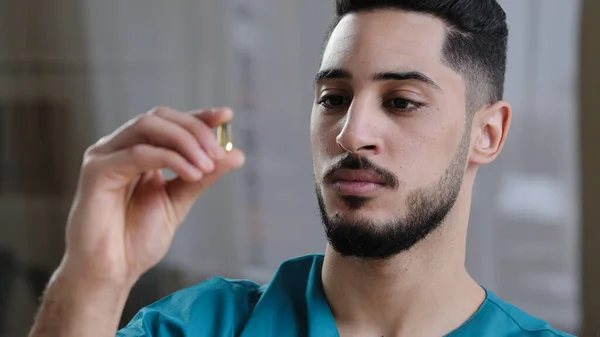 Fiatal tudós spanyol férfi orvosi alkalmazott kezében átlátszó kapszula tabletta kezében arab orvos elemzése tanulmányozza tulajdonságait kábítószer modern klinikai kutatás gyógyszeripar — Stock Fotó