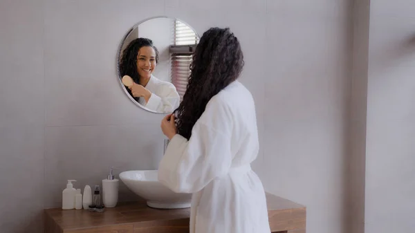 Young happy woman standing in bathroom looking in mirror touching face after applying cream enjoys healthy moisturized skin admiring herself dancing singing enjoying energetic morning hygienic routine — Stock Photo, Image