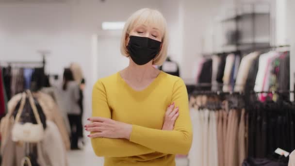 成功した成熟した中年女性売り手コンサルタント服店の所有者で医療マスク立って自信を持ってカメラを見て腕を組んで胸の上に交差小さなビジネスコンセプト — ストック動画