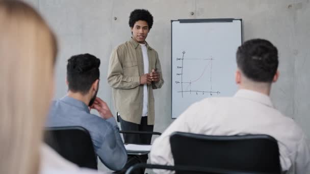 Jeune homme gestionnaire présentant le plan de projet à ses collègues dans une réunion expliquant les idées de calendrier de rapport sur le tableau blanc au bureau faire une présentation discuter de la stratégie de travail avec une équipe d'affaires diversifiée — Video