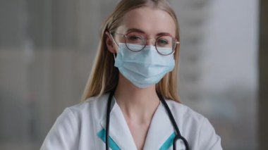 Kafkasyalı doktor portresi. Gözlüklü, tıbbi koruyucu yüz maskesi takan, doktor, cerrah kadın. Kameraya bakıyor.