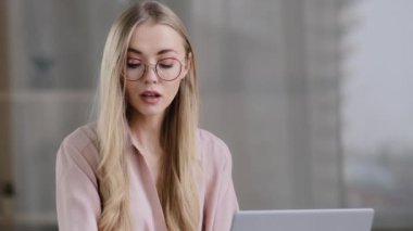 Kafkasyalı iş kadını gözlüklü serbest sekreter kız ofiste dizüstü bilgisayarla çalışıyor müşteri telefonlarına cevap veriyor satış müdürüyle cep telefonu görüşmesi yapıyor internetten akıllı telefon siparişini alıyor