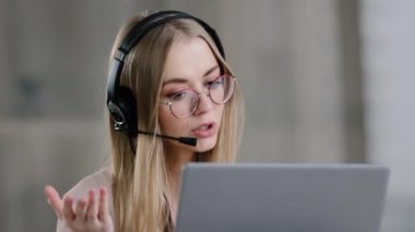 Kafkasyalı genç kız yardım hattı yöneticisi mikrofonlu kulaklık takıyor dizüstü bilgisayarda web kamerasına bakıyor net video sınıfında online danışmanlık sigortası eğitimi alıyor.