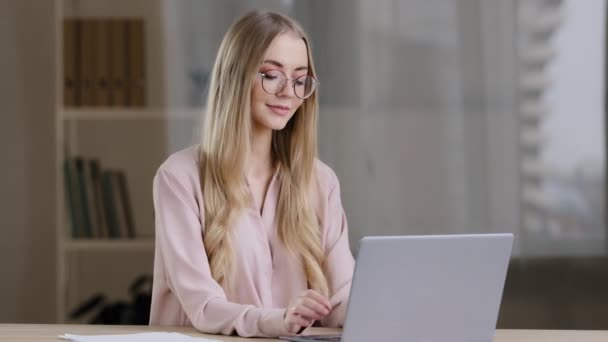 Kaukaski millenium biznes kobieta uczennica dziewczyna pisarz dziennikarz noszenie okularów siedzi przy stole w biurze domu z laptopem myśli pomysł wyobraźnia kreatywne pisanie używa bezprzewodowej aplikacji komputerowej — Wideo stockowe