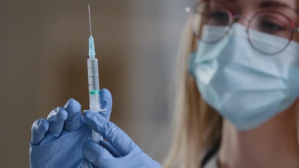 여성의 얼굴을 보호하는 의료용 마스크를 쓴 의사가 주사 코비 19 백신 접종을 위한 주사기를 들고 있는 모습은 극도로 자세하다. 항생제 항 바이러스 백신을 사용하는 여성 간호사 — 비디오