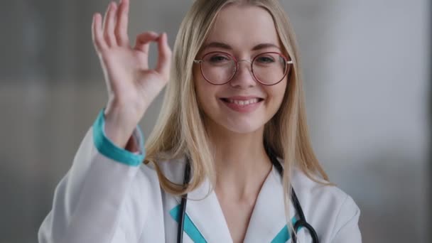 Portrait caucasien heureux médecin praticien spécialiste thérapeute infirmière travailleuse médicale femme dans les lunettes regarder la caméra montre ok geste recommande une bonne santé santé santé bien grande — Video