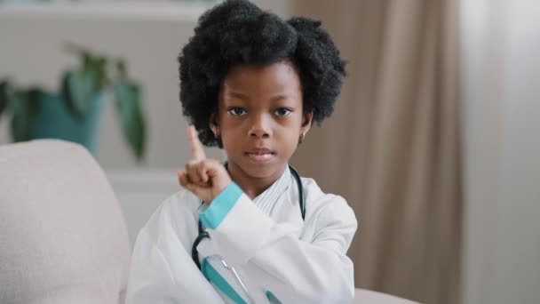 Retrato pouco grave criança menina no médico vestido fingindo ser médico jogando no hospital olhando para câmera posando negativamente acenando dedo Nenhum gesto mostrando símbolo desaprovação proibição repreensão — Vídeo de Stock