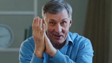 Yaşlı kırışıkların portresi, odada oturan hayranlığını dile getiren beyaz saçlı dede kameraya bakıp el çırpıyor yetişkin emekliler samimi tezahürat onayını kutluyor.