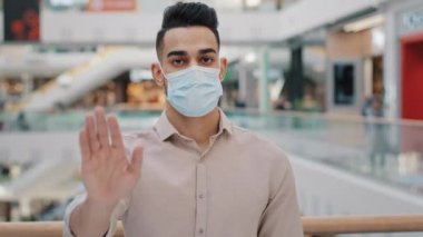 Tıbbi maske takan İspanyol bir gencin portresi avuç içini öne çıkardı. Ciddi bir Arap erkeği el hareketi ile dur işaretine bakıyor. Güvenli mesafe koronavirüs salgını koruma kavramı.