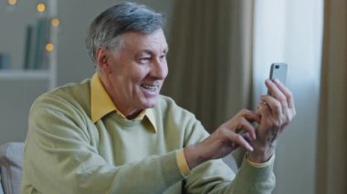 Mutlu yaşlı yetişkin adam telefon ediyor gülümsüyor büyükbaba akıllı telefon ekranına bakıyor modern cihaz kullanıyor yaşlı erkek telefonda konuşuyor iyi haber