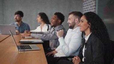 Genç çok ırklı ofis çalışanları, sunum çalışanlarının gülümsemesini izliyorlar yönetim kurulu yatırımcılarında onaylayıcı bir şekilde konferans dinliyorlar yeni başlatılan proje uluslararası şirket yönetim röportajını değerlendiriyorlar