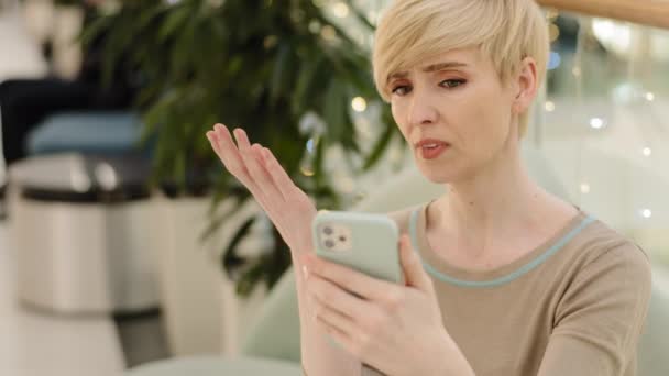 Stresli yetişkin 40 'lı yaşlarda kadın cep telefonu ekranına bakıyor. Spam mesajı almaktan hayal kırıklığı yaşıyor. Kötü haber. — Stok video