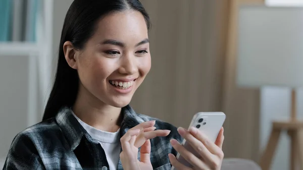 Cep telefonu ekranına bakıp gülümseyen Asyalı kadın blogcunun ev portresi. Sevgilisiyle mesajlaşmak, sohbet etmek. Alış veriş uygulamasında ürünü seçen mutlu akıllı telefonlu mutlu müşteri. — Stok fotoğraf