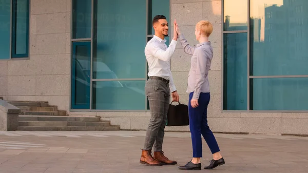 Två vänliga multiracial kollegor företag medarbetare arabiska latinamerikanska man och kaukasiska kvinna träffas utomhus på gatan gör high five hands gest informell hälsning försvinner i olika direkt — Stockfoto