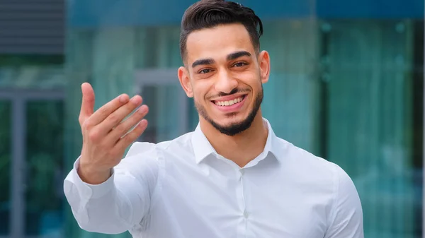 Portrait friendly smiling toothy hispanic arab business man spaniard boss wears white formal shirt showing gesture of invitation advice to approach with hand asks to come outdoors, body languages sign — Stock Photo, Image