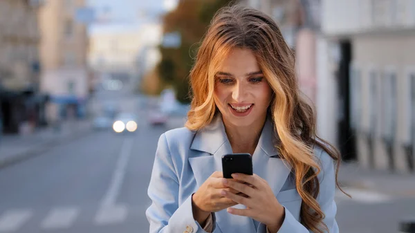 Portret kaukaski dziewczyna biznes kobieta patrząc w telefon komórkowy raduje się zwycięstwo dobra wiadomość czat w sieci otrzymuje wiadomość od chłopaka udany e-commerce zakup online stojąc w mieście — Zdjęcie stockowe