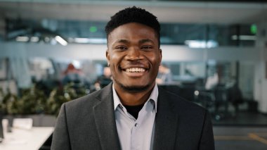 Yakışıklı afro-amerikan çok ırklı girişimci işadamı ofiste dikiliyor profesyonel erkek takım elbiseli patron kameraya bakıp gülümsüyor.