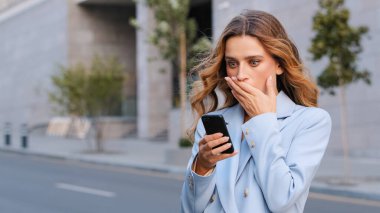 Kafkasyalı iş kadını dışarıda cep telefonu tutuyor hoş olmayan mesajlar okuyor korkunç haberler ağızlarını kapatıyor. Banka hesaplarını bloke etmiş, akıllı telefon şokunu atlatmış.