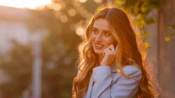 Portrait de belle succès jeune femme d'affaires caucasienne millénaire fille modèle féminin se tient à l'extérieur dans la ville lever du soleil arrière-plan du coucher du soleil parler sur téléphone mobile réponses appel appel parler — Photo