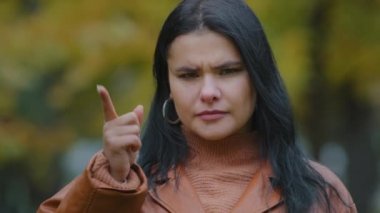 Yakın plan portre genç sinirli ciddi İspanyol kadın dışarıda kameraya bakıyor sert bir şekilde el sallıyor, parmağını sallıyor onaylamama işaretini yasaklıyor hoşnutsuzluk belirtileri gösteriyor.