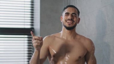 Neşeli, mutlu, dertsiz, Hintli, Arap, çıplak adam banyoda şarkı söylüyor, sabah hijyeninde dans ediyor. Komik seksi erkek müzik dinliyor hareketli dans ediyor banyoda yıkıyor