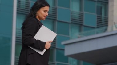 İş elbisesi giymiş, ciddi şekilde yorgun genç bir iş kadını arka planda ofis binasına karşı yürüyor elinde dizüstü bilgisayarla, gündüzleri dışarıda tek başına yürüyen İspanyol bir kadın olduğunu sanıyordu.
