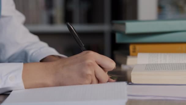 Close-up kobiet ręce nierozpoznawalne kobieta uczeń nauczyciel siedzi w bibliotece uniwersyteckiej przygotowując egzamin lekcyjny robi pracę domową pisanie streszczenie w notatniku pisze notatki w zeszycie ćwiczeń z podręcznika — Wideo stockowe