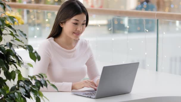 Ασιάτισσα φοιτήτρια Κορεάτισσα επιχειρηματίας συγγραφέας δημοσιογράφος που κάθεται σε καφετέρια στο γραφείο με laptop πληκτρολογώντας bookouts κρατήσεις ταξίδια χρησιμοποιώντας δωρεάν Wi-Fi εργασίας μελετώντας με εφαρμογή υπολογιστή — Αρχείο Βίντεο