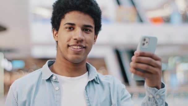 Portret zadowolony zadowolony Afryki facet z telefonu smartfon nowoczesny gadżet patrząc na kamery pokazuje jak kciuki do góry zaleca wifi połączenie komórkowe 5g mobilna strona promocji aplikacji dobra sieć — Wideo stockowe