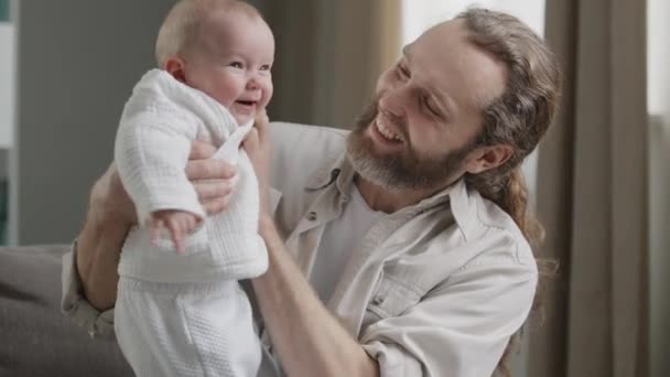 Счастливая кавказская семья на дому игра бородатый отец с маленькой дочерью ребенок новорожденный ребенок воспитания ребенка прыжки смех прыжки смех весело эмоции родительские опекунство концепции — стоковое видео
