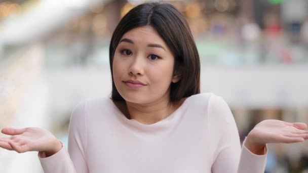 Портрет азиатской корейской неуверенной смущенной девушки, образцовой студентки, не подозревающей, что 20-летняя женщина бросает руки в стороны, делая жест сомнения выражает точно неизвестный знак неопределенности — стоковое видео