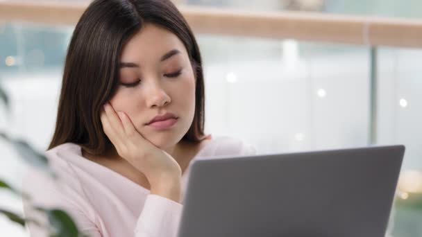 Trött ledsen upprörd kvinnligt ansikte utmattad missnöjd asiatisk kvinnlig chef arbetare student flicka tittar på bärbar dator med uttråkad försöker arbeta på morgonen på kontoret läsa dåliga nyheter tråkig arbetsrutin lättja — Stockvideo