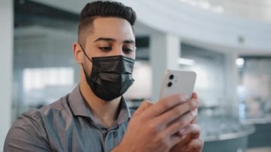 Medikal yüz maskesi takan Arap Hintli işadamı, ortaklarıyla resmi tişört sohbeti yapıyor. Uzaktan kumandalı danışman ile cep telefonlu şirket mesajları kullanıyor.