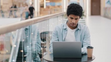 Afrika kökenli Amerikalı ciddi bir milenyum işadamı erkek serbest çalışan öğrenci kullanıcı kahve masasında oturuyor dizüstü bilgisayarla e-öğrenim çalışması internet ekommersi