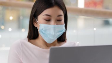 Hüzünlü Asyalı iş kadını portresi. Yüzü maske takan kız öğrenci. Laptop projesiyle birlikte tıbbi maskesini çıkarıyor.