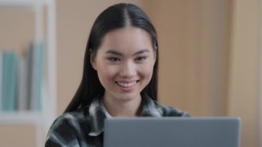 Asyalı gülümseyen kız kullanıcı serbest kullanıcı blogcu iş kadını 20 'li yaşlardaki bayan bilgisayar uygulaması internet sitesi sohbeti kullanarak samimi bir gülümsemeye bakıyor.