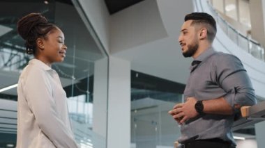 İki mutlu dost canlısı iş ortağı iş arkadaşı Afrikalı kadın yönetici kadın işkadını ve erkek işadamı ofis şirketinde konuşuyorlar ve beşlik bir başarı için ortaklık kuruyorlar.