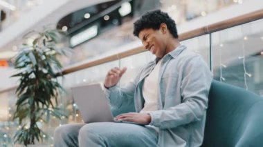 Çok ırklı bir adam serbest çalışan üzgün bir iş adamı dizüstü bilgisayarı ile koltukta oturmuş online bahis kaybediyor internet açık arttırmasında para kaybediyor hisse senedi düşüşü kötü sonuç başarısız