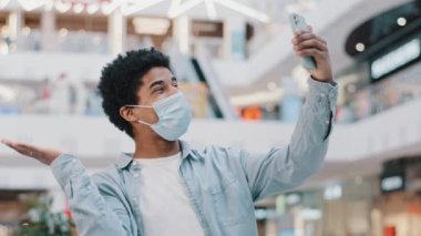 Portre Afro-Amerikan erkek öğrenci erkek öğrenci kapalı alanda cep telefonu kullanıyor merhaba diyor görüntülü konuşma konferansı arkadaşlarıyla uzaktan konuşma akıllı telefon ile uzaktan konuşma iletişimi