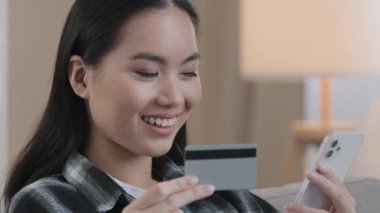 Banka kartı ve cep telefonlu Asyalı Koreli Çinli kız internet üzerinden elektronik ödeme alışverişi yapıyor. İnternet üzerinden e-ticaret rezervasyonu siparişi alıyor.