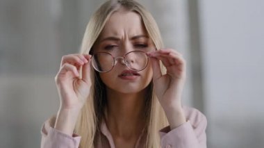 Yakın plan kadın portresi. Milenyum 30 'lu yaşlarda zayıf görme yeteneği olan sarışın bir kadın. Gözlüğünü çıkarıyor.