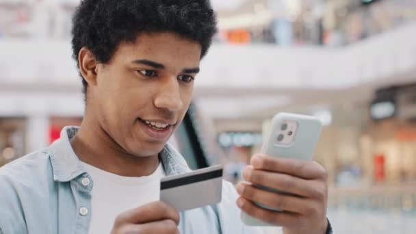 Afro-Amerikaanse attente man klant invoeren van bankkaart gegevens in telefoon mobiel betaalt aankoop kiezen van goederen online beslist internet betaling financiële transfers virtueel geld netto app — Stockvideo