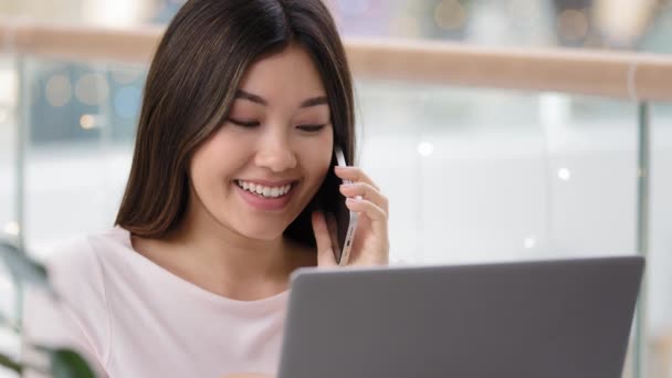 Headshot asian businesswoman professional adviser freelancer woman talking on phone with customer client distant consultation chatting with friend using laptop booking good delivery using mobile call — Stock Video