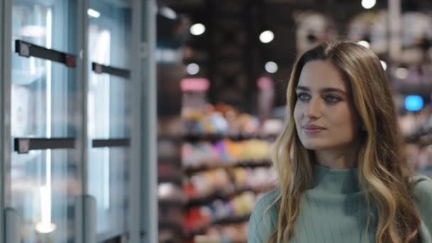 Close-up caucasiano 30 anos menina comprador consumidor cliente mulher dona de casa menina andando perto de geladeira em supermercado supermercado loja escolher produtos dieta saboroso comércio de alimentos conceito de nutrição — Vídeo de Stock