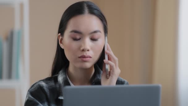 Komoly 20-as évek ázsiai etnikai üzletasszony szakmai szabadúszó nő lány beszél telefonon ügyfélszolgálat segítségével laptop ülni otthon mobil hívás online website shopping order delivery — Stock videók